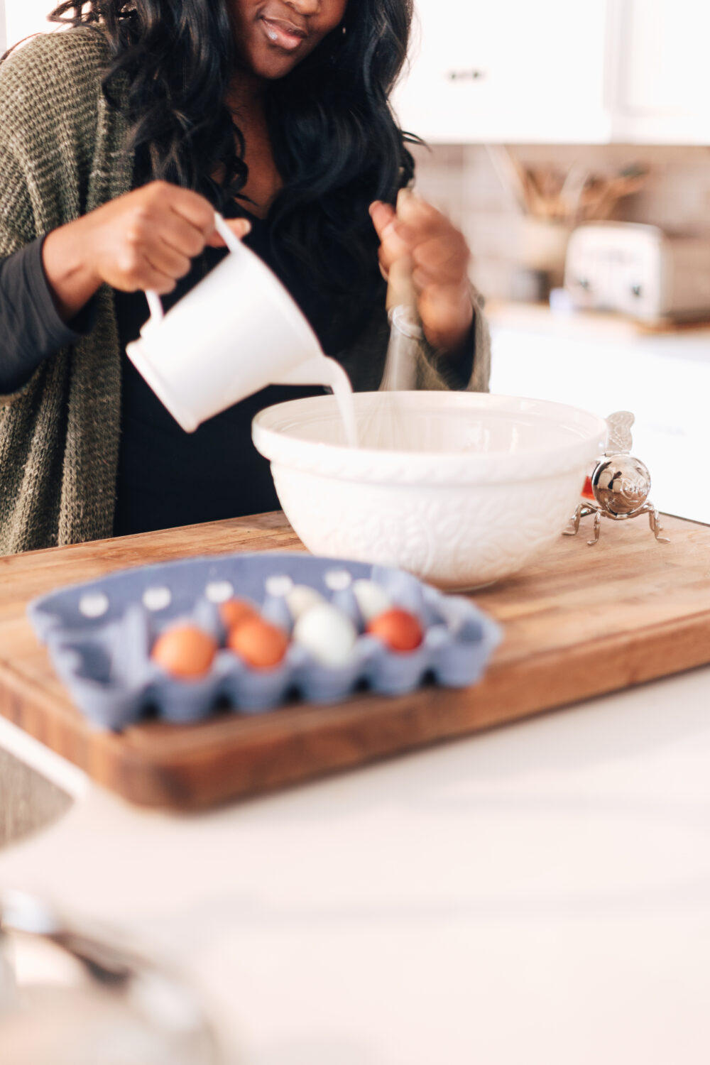 Make waffles with a white bowl. Woman pouring milk and other ingredients into a bowl.