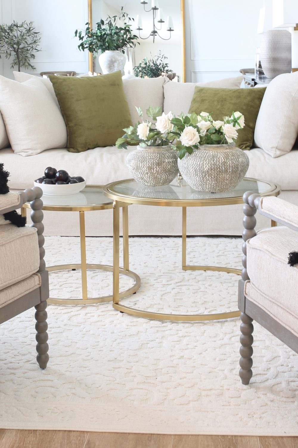 White living room with gold nesting tables. The rug is also white.