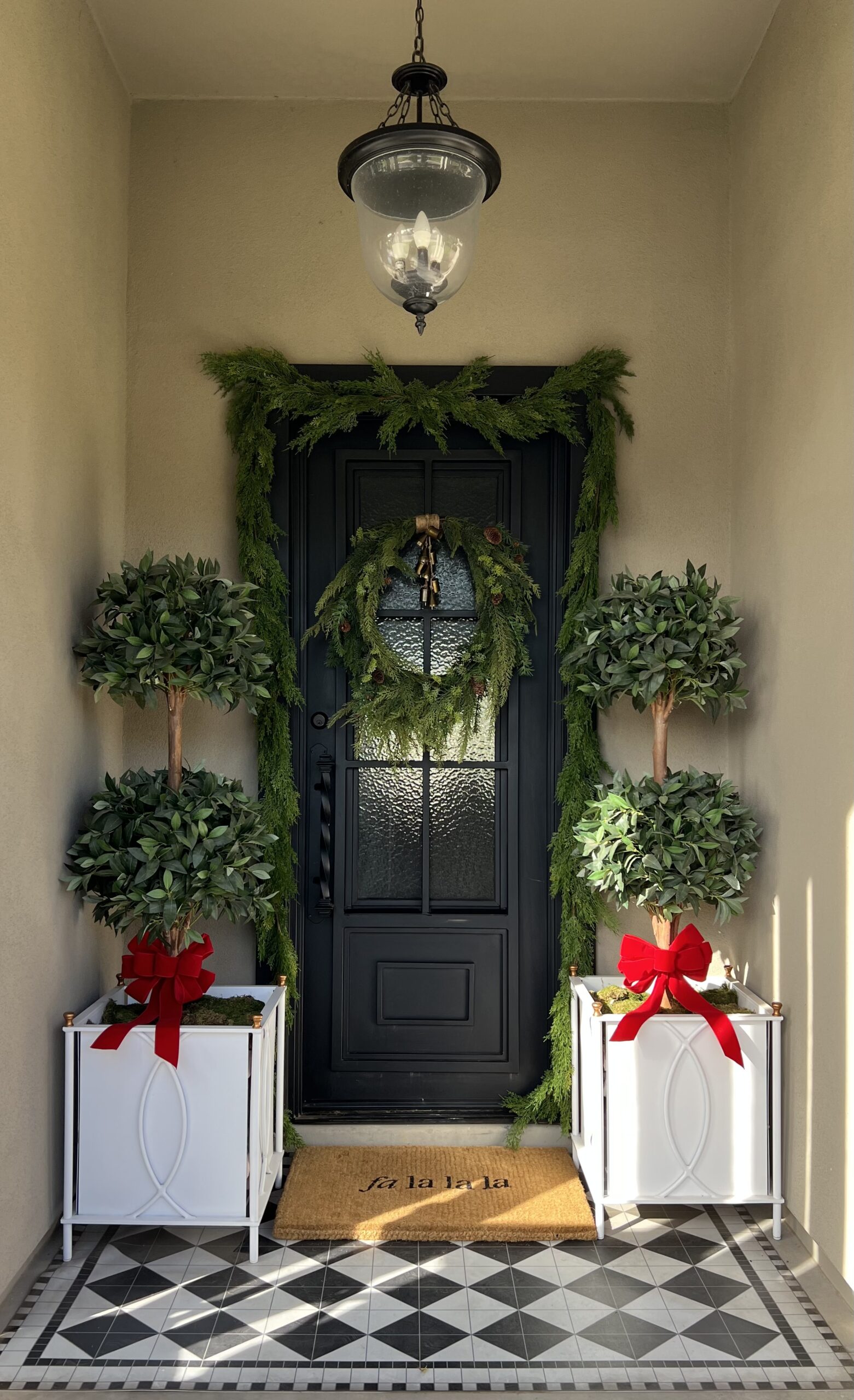 Front door with red ribbons and white planters.