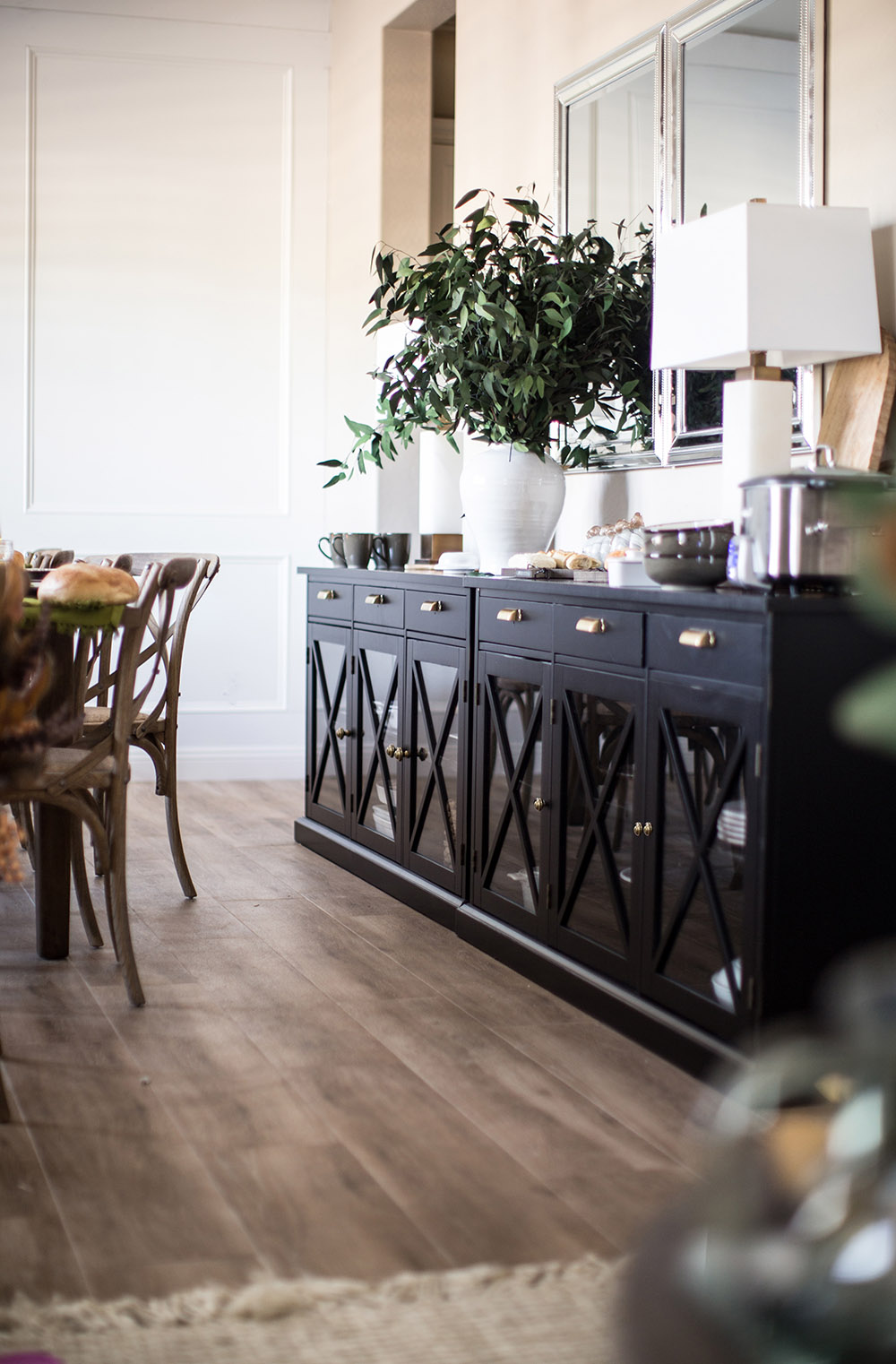 Dining room with long black buffert with lamps and other accesories.