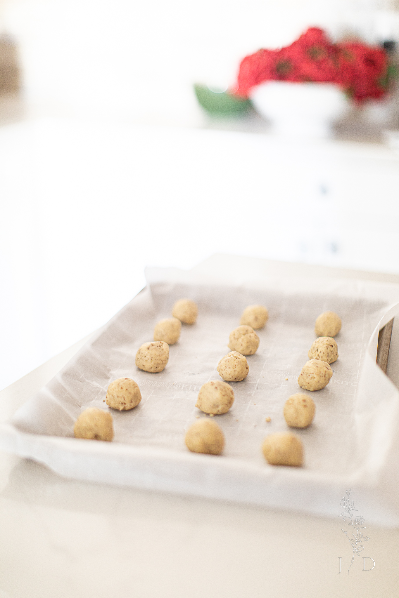 Small rows of rolled Mexican Christmas cookie dough getting ready to bake. The cookie dough is on parchment paper. 