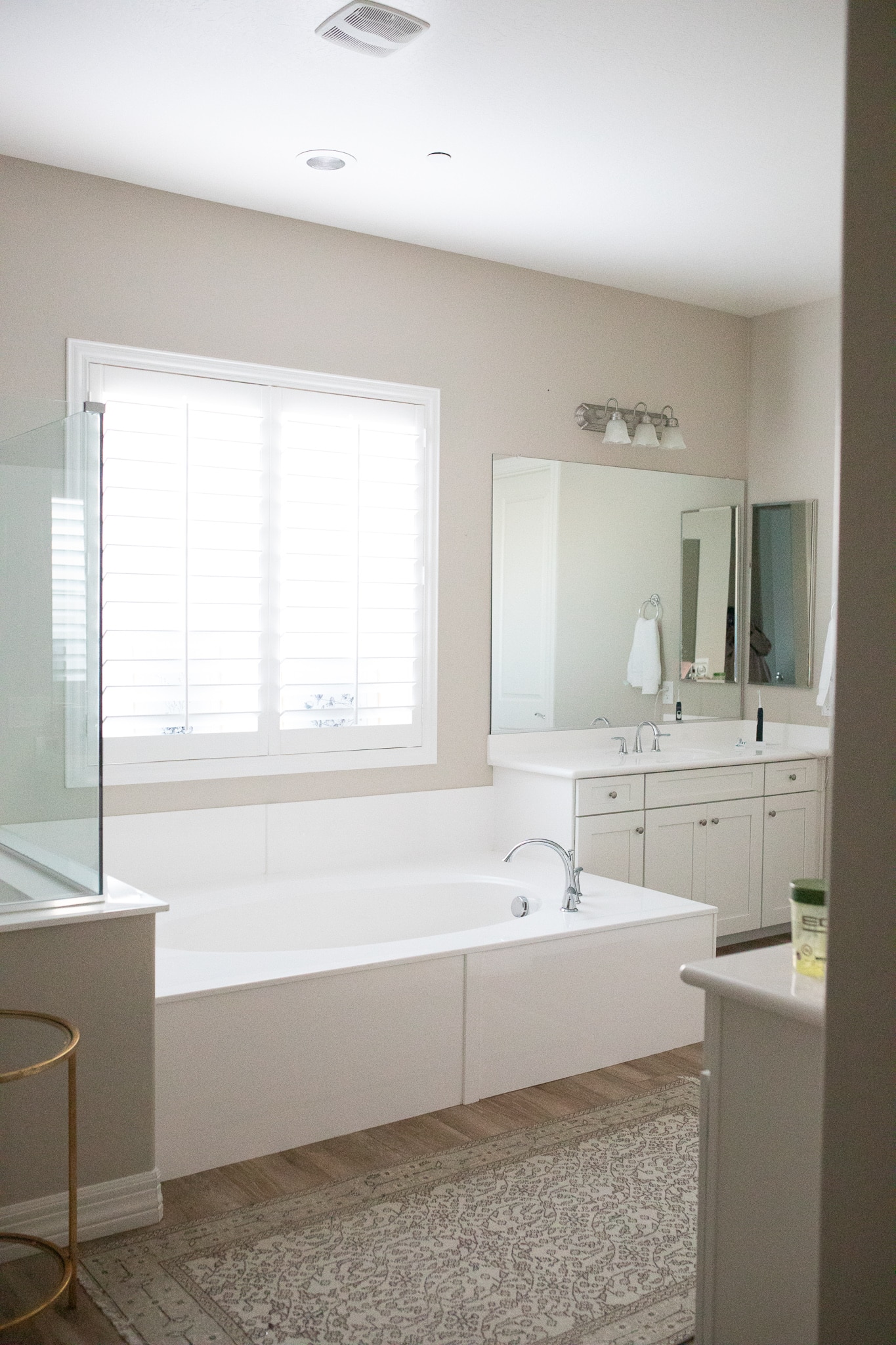 Shot of a bathroom before makeover wood tile floors with builder basic vanities and white tub. 