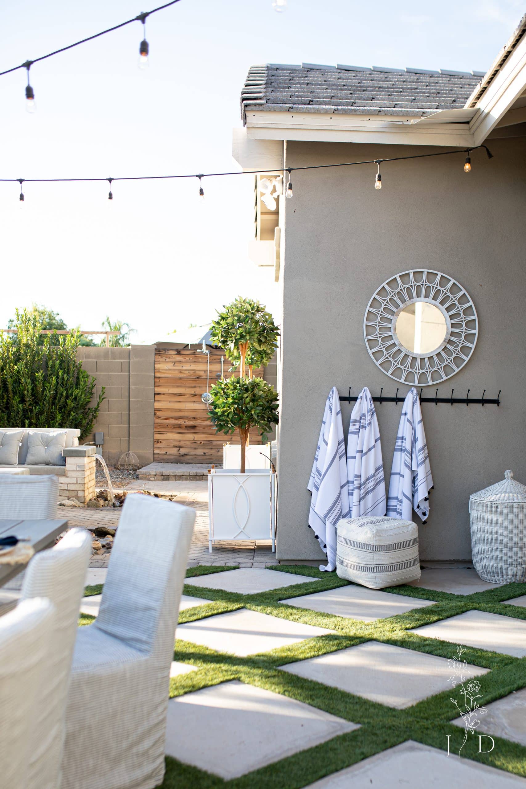 Outdoor scene in a backyard. Green x grass and pool towels hanging on hooks.