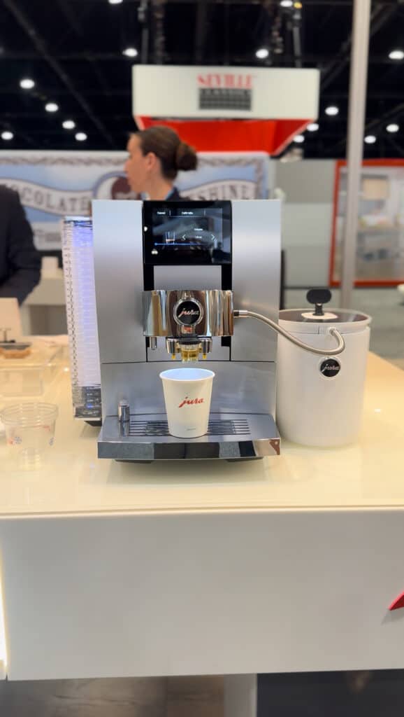 High-quality espresso machine brewing coffee at a trade show booth.